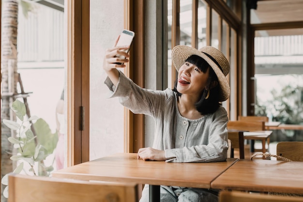 Portret szczęśliwej kobiety, która sama robi selfie w kawiarni