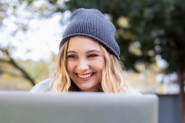 Portret szczęśliwej młodej kobiety korzystającej z laptopa na zewnątrz