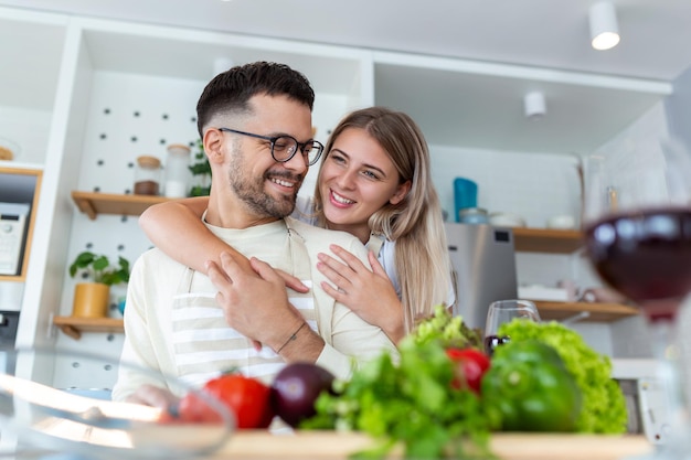 Portret szczęśliwej młodej pary gotowanie razem w kuchni w domu romantyczny Atrakcyjna młoda kobieta i przystojny mężczyzna cieszą się spędzaniem czasu razem stojąc na lekkiej nowoczesnej kuchni
