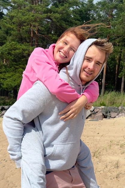 Zdjęcie portret szczęśliwej młodej pary spacer po plaży, miłość, przytulenie, facet niesie swoją dziewczynę
