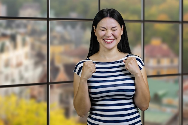 Portret szczęśliwej młodej ślicznej azjatyckiej kobiety świętującej sukces w szachownicę z widokiem na jesień l