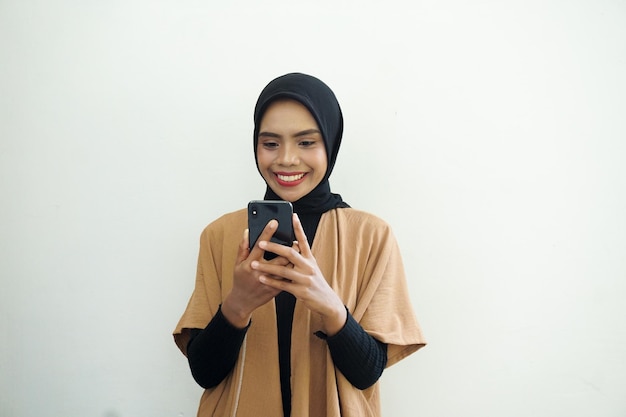 Portret szczęśliwej muzułmańskiej kobiety noszącej chustę na głowie i trzymającej telefon