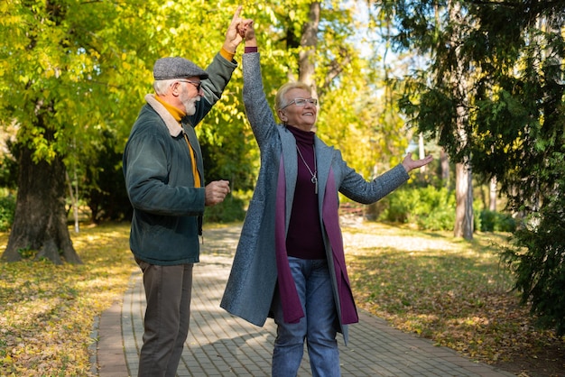 Portret szczęśliwej pary seniorów tańczącej w parku