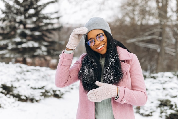 Portret szczęśliwej pozytywnej dziewczyny African American młoda kobieta w okularach i rękawiczkach w winter park