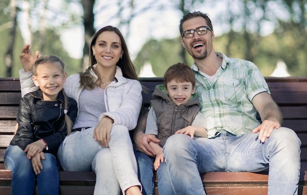 Portret szczęśliwej rodziny siedzącej na ławce w parkurodzinny wypoczynek