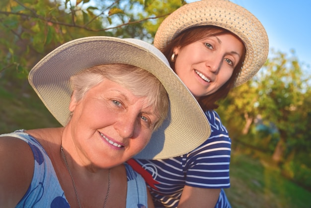 Portret szczęśliwej starszej kobiety przytulanie córki i sprawia, że selfie