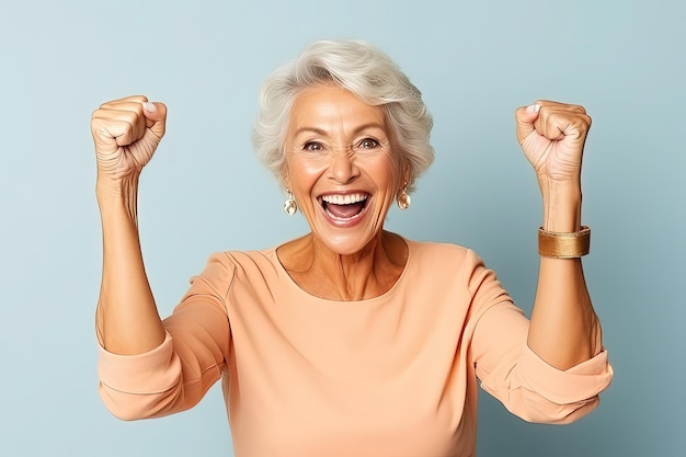 Portret szczęśliwej starszej kobiety świętującej sukces odizolowanej na niebieskim tle