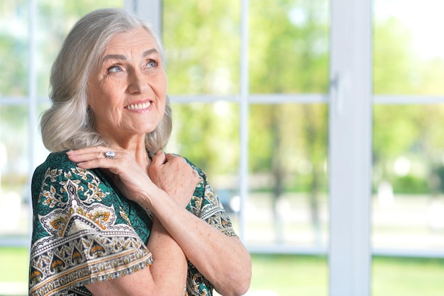 Portret szczęśliwej starszej kobiety w zielonej koszuli pozuje w domu