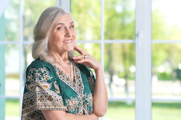 Portret szczęśliwej starszej kobiety w zielonej koszuli pozuje w domu