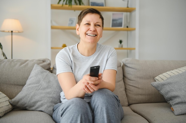 Portret szczęśliwej starszej kobiety zmieniającej kanał w telewizji