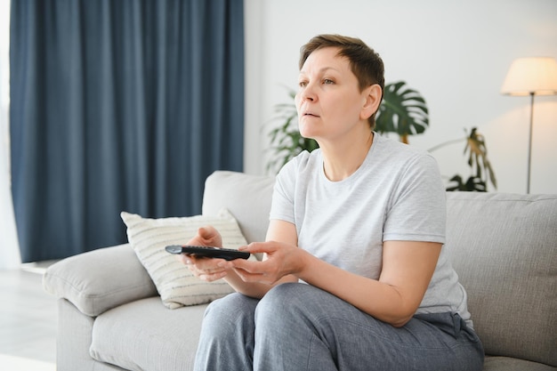 Portret szczęśliwej starszej kobiety zmieniającej kanał w telewizji