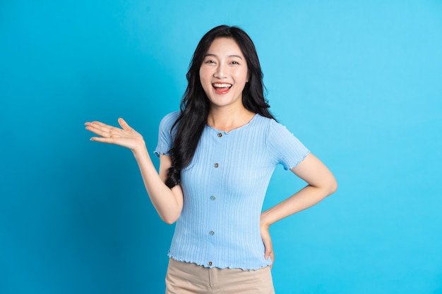 Portret szczęśliwej uśmiechniętej azjatyckiej dziewczyny pozuje na niebieskim tle