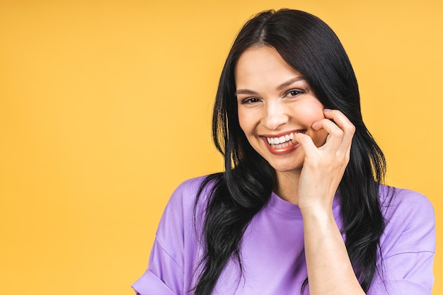 Portret szczęśliwej uśmiechniętej brunetki w swobodnym, odizolowanym na żółtym tle