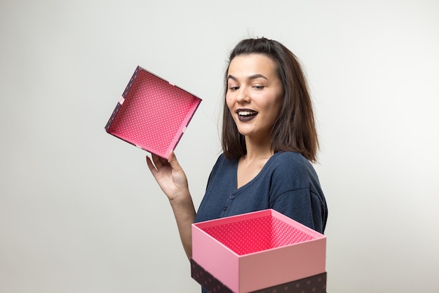 Portret szczęśliwej uśmiechniętej dziewczyny otwierającej pudełko z prezentami na białym tle nad białym tłem