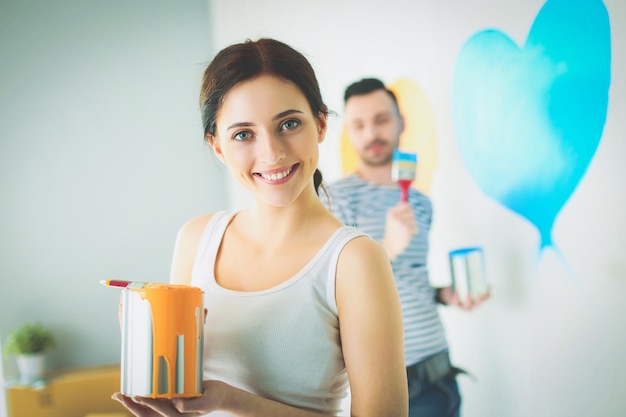 Portret szczęśliwej uśmiechniętej młodej pary malującej wewnętrzną ścianę nowego domu młodej pary