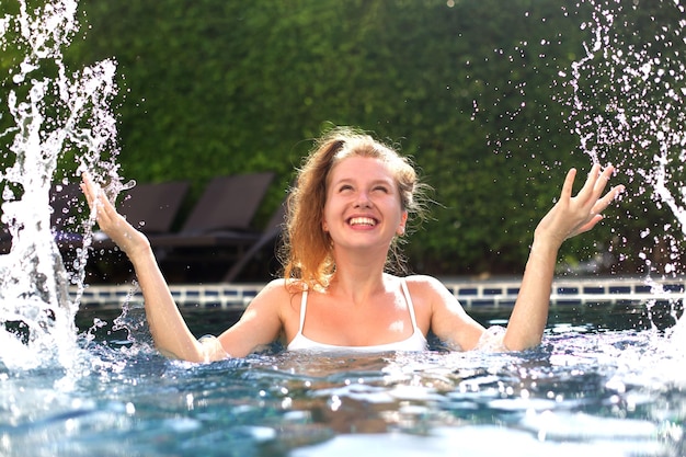 Portret szczęśliwej, wesołej młodej kobiety, która dobrze się bawi pływając w basenie na świeżym powietrzu w słoneczny letni dzień