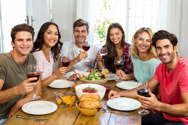 Portret szczęśliwi przyjaciele trzyma win szkła podczas gdy mieć lunch