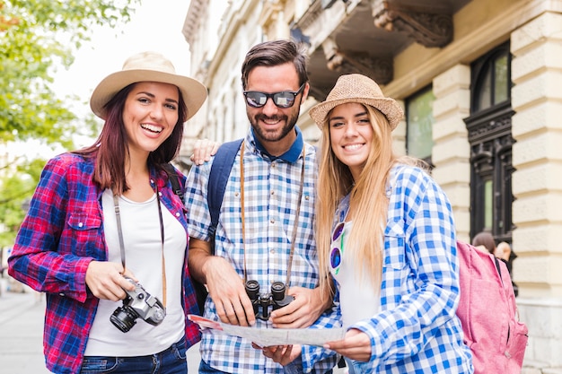 Portret szczęśliwi przyjaciele z mapą przy outdoors