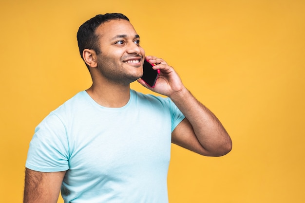 Portret szczęśliwy african american black indian człowiek rozmawia przez telefon komórkowy na białym tle nad żółtym tle.