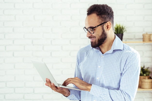 Portret szczęśliwy afroamerican mężczyzna używa laptopu comruter