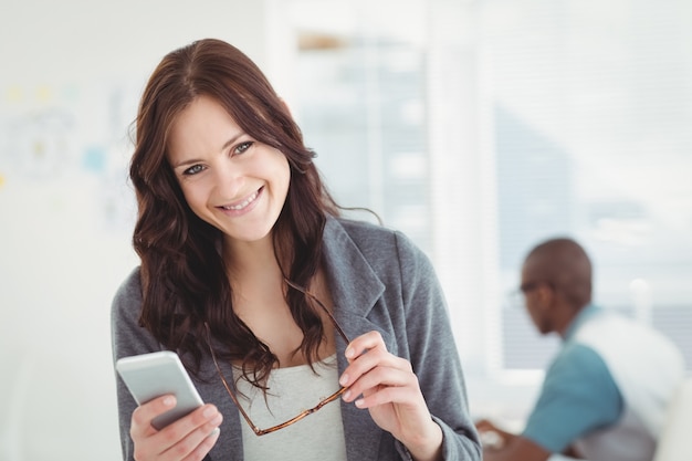 Portret szczęśliwy bizneswomanu mienia eyeglasses i smartphone