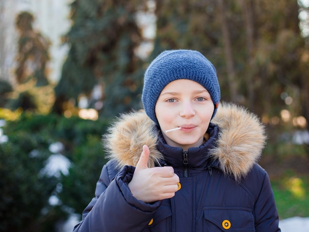 Portret szczęśliwy chłopiec Wyświetlono kciuki do góry gest, zimny sezon