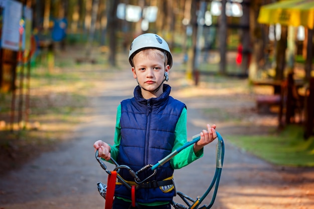 Portret szczęśliwy chłopiec zabawy w parku rozrywki, uśmiechając się do kamery na sobie kask i sprzęt bezpieczeństwa.