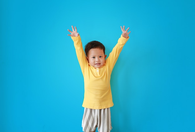 Portret Szczęśliwy Mały Azjatycki Chłopiec Wyrażenie Podnieść Ręce I Patrząc Na Aparat Odizolowany Na Niebieskim Tle.