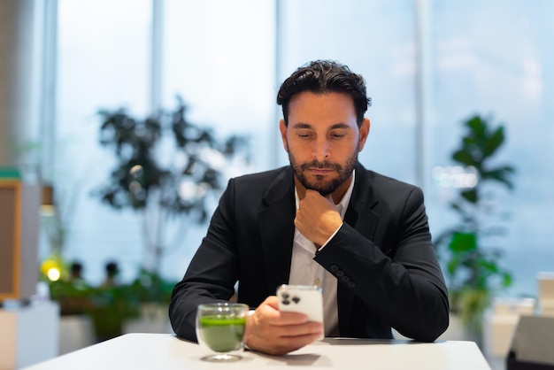 Portret szczęśliwy przystojny Hiszpanie biznesmen w kawiarni po zieloną herbatę i przy użyciu telefonu