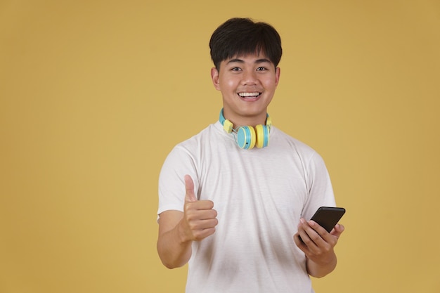 Portret szczęśliwy radosny wesoły młody azjatycki człowiek w słuchawkach, słuchanie muzyki na smartfonie i taniec na białym tle