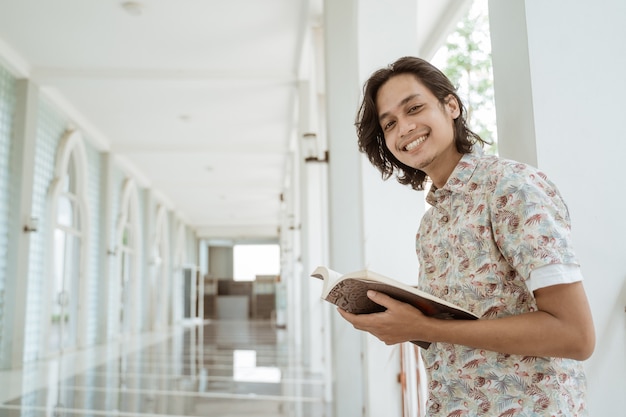 Portret Szczęśliwy Studentka Trzymając Książkę I Patrząc Na Kamery W Kampusie.