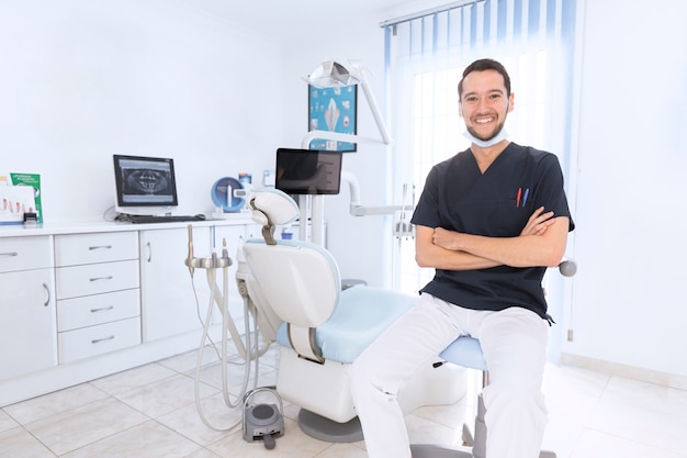 Portret szczęśliwy ufny dentysta w klinice
