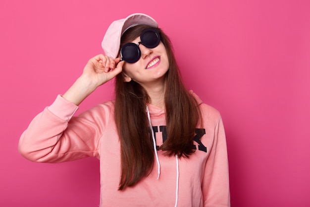 Portret szczęśliwy uśmiechnięty kaukaski brunetka nastolatka w stylowej krótkiej różowej bluzie z kapturem