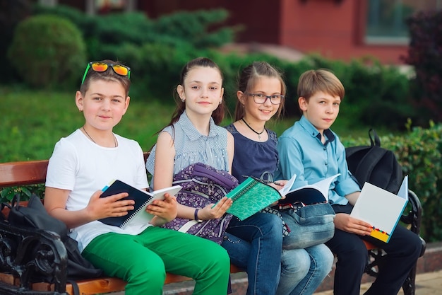 Zdjęcie portret szczęśliwych kolegów. koledzy siedzący z książkami na drewnianej ławce w parku miejskim i studiujący w słoneczny dzień.