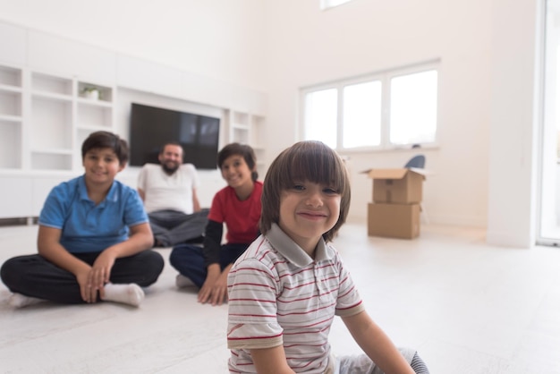 portret szczęśliwych młodych chłopców z tatą siedzących na podłodze w nowym nowoczesnym domu