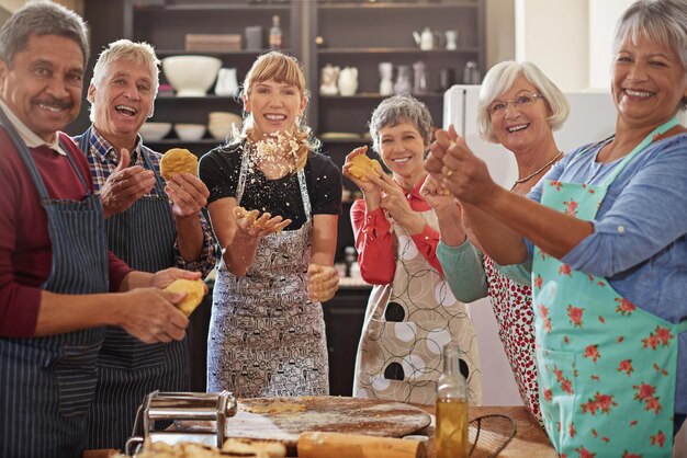 Zdjęcie portret szczęśliwych starszych ludzi bawiących się w kuchni i na lekcjach gotowania osiągnięcie lub sukces współpraca w zakresie pieczenia lub gotowania i praca zespołowa grupy osób starszych wiwatujących lub świętujących razem