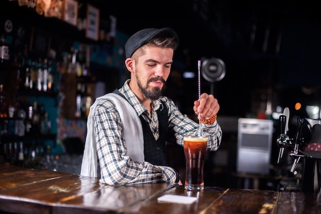 Portret tapstera wykonuje ostatnie szlify na drinku na barze