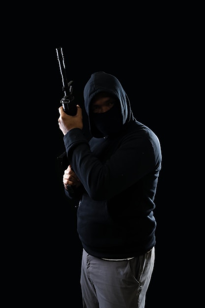 Portret terrorysty w czarnej bluzie z kapturem trzymającego karabin M16 – koncepcja terroryzmu