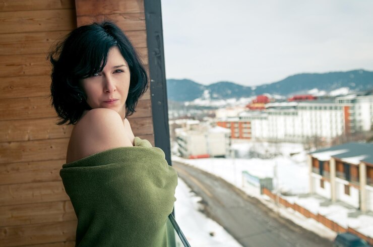 Zdjęcie portret topless kobiety z kocem stojącej na balkonie