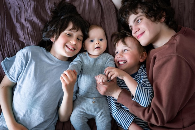 Zdjęcie portret trzech braci leżących na łóżku z rodzeństwem pozytywnych dzieci w różnym wieku duża koncepcja rodziny szczęśliwa razem