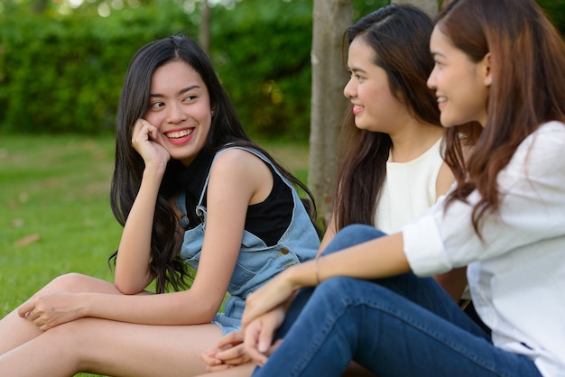 Portret trzech młodych azjatyckich kobiet jako przyjaciół razem relaks w parku na świeżym powietrzu