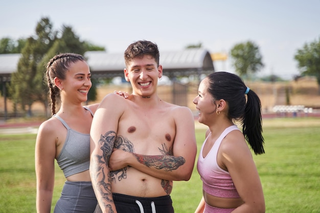 Portret trzech sportowych przyjaciół w parku, uśmiechając się i dobrze się bawiąc