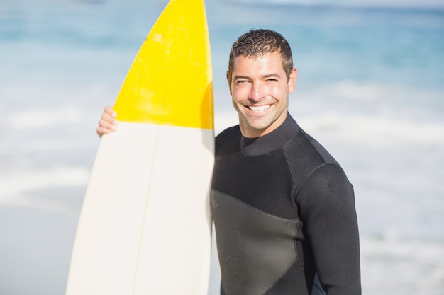 Portret trzyma surfboard na plaży szczęśliwy mężczyzna
