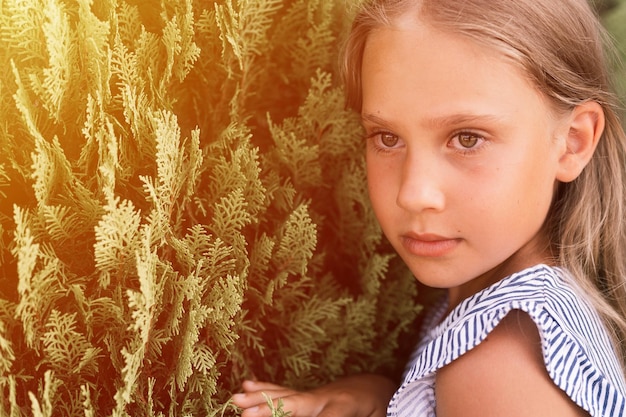 Portret twarz szczery obrażony zdenerwowany małe dziecko dziewczynka w wieku ośmiu lat z długimi blond włosami na tle zielonych roślin podczas letnich wakacji podróży gen z koncepcja zdrowia psychicznego pochodni