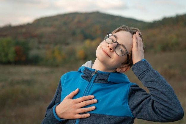 Portret u?miechni?tego nastoletniego ch?opca w okularach na górskim tle krajobrazu Dziecko na spacerze w przyrodzie jesienią