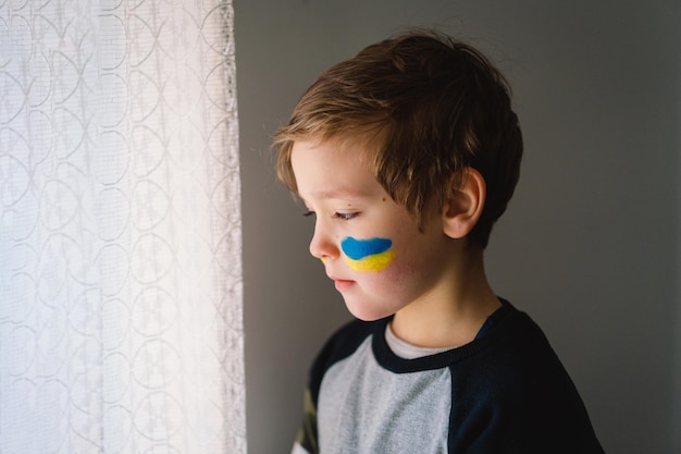 Portret ukraińskiego chłopca z twarzą pomalowaną kolorami ukraińskiej flagi