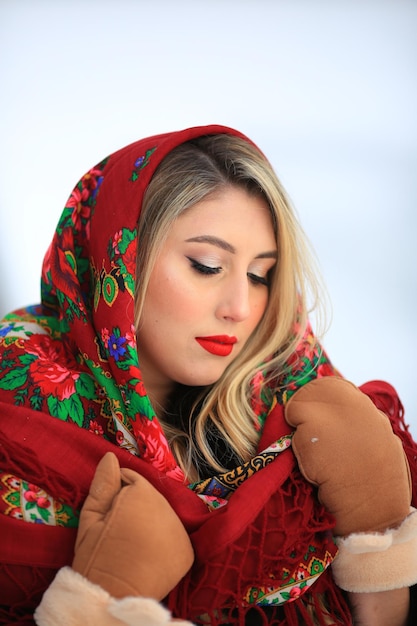 Portret ukraińskiej dziewczyny w tradycyjnej czerwonej chustce Ciepłe brązowe rękawiczki na rękach Blondynka