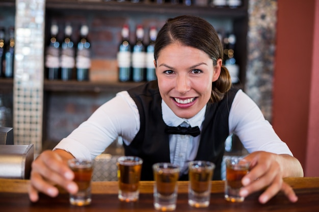 Portret umieszcza strzałów szkła na baru kontuarze barman