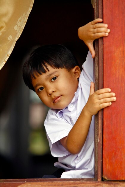 Zdjęcie portret uroczego chłopca patrzącego przez okno