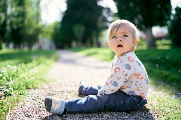 Portret uroczego chłopca siedzącego na lądzie